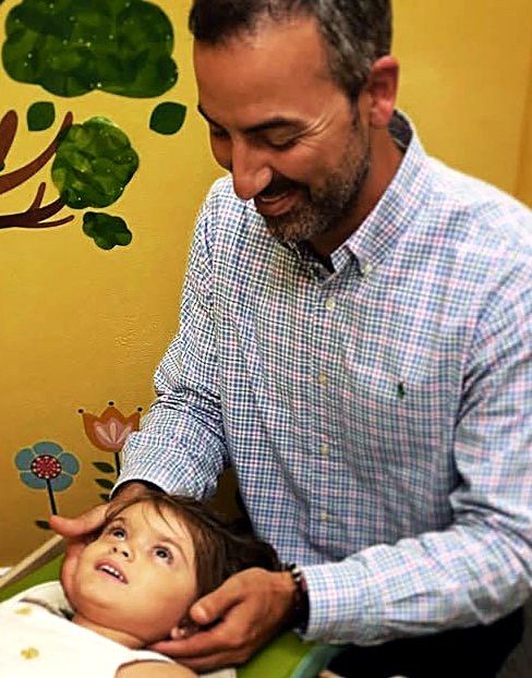 Dr. Braglia gently adjusting a young child